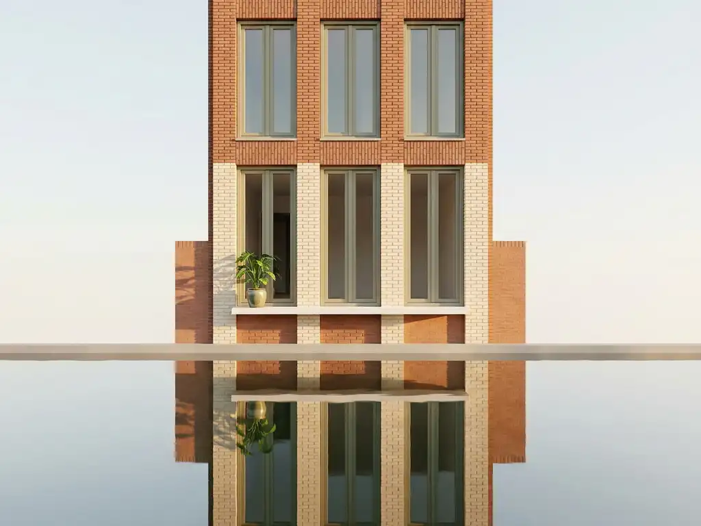 Narrow Amsterdam canal house facade in terracotta brick reflected in still water, tall windows with a potted plant on a white sill in golden morning light.